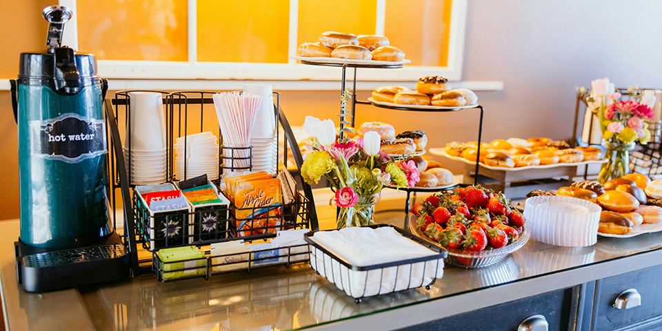 Pult za doručak sa krofnama, stanicom za napitke i kondimentima.