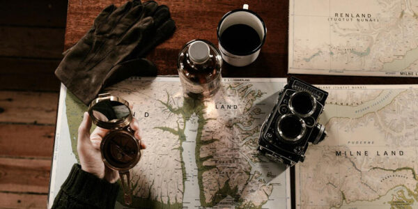 Jedna ruka drži kompas dok druga pokazuje lokaciju na karti