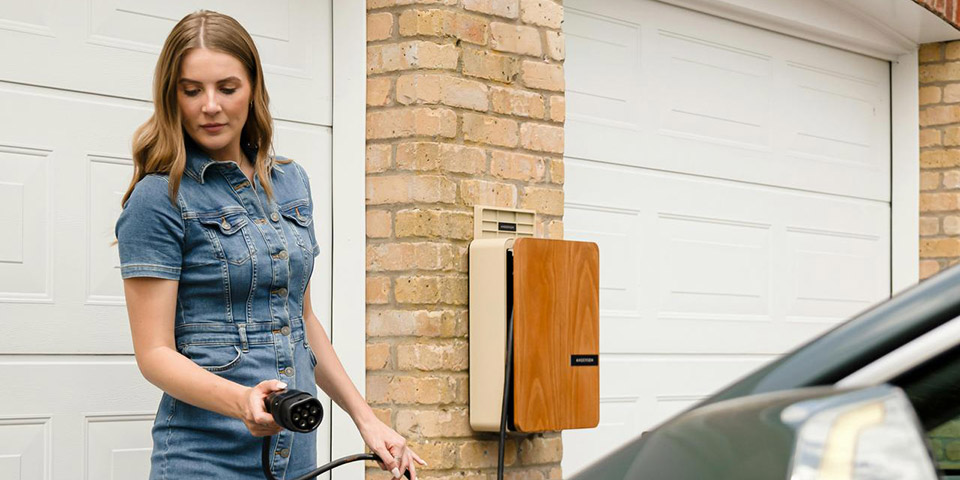 Žena povezuje kabl za punjenje u priključak električnog automobila