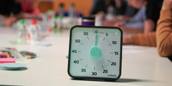 Tajmer na stolu ispred zamućenih ljudi tokom sastanka