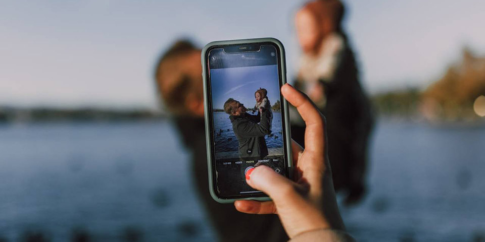 Osoba telefonom fotografiše dete i čoveka