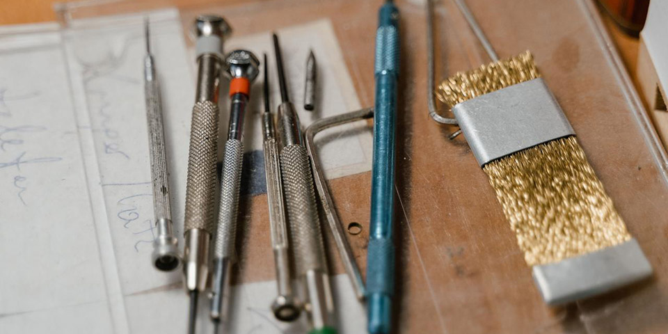 Set metalnih preciznih odvijača i zlatna žičana četkica na prozirnoj plastičnoj podlozi
