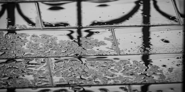 Refleksija crnih oblika na mokrim pločicama sa kapljicama vode