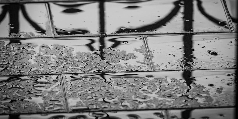 Refleksija crnih oblika na mokrim pločicama sa kapljicama vode