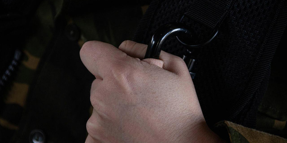 Ruka drži crni karabiner pričvršćen za crni remen